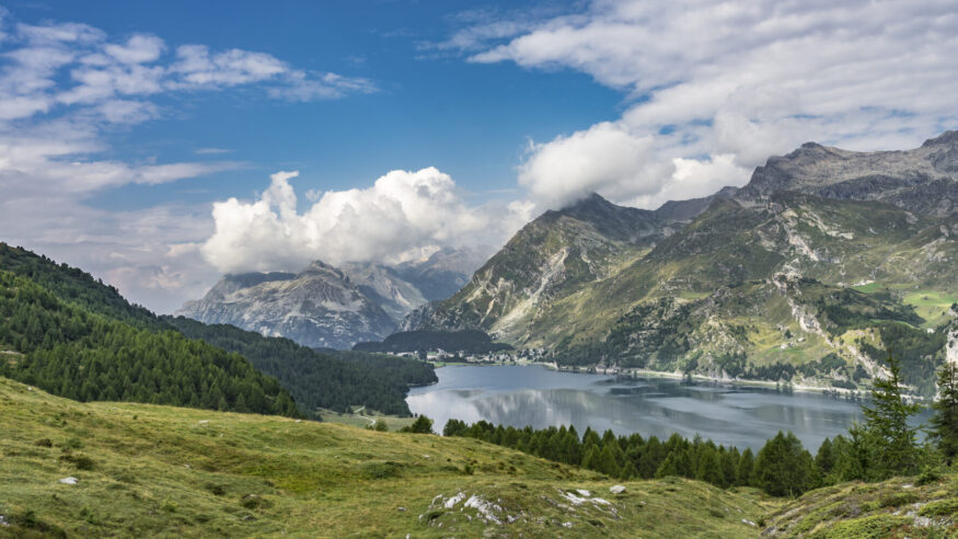 Senior woman, riding here e-mountain bike on the famous trails around the lakes in the upper Engadin, between Saint Moritz and Maloja, Engadin, Switzerland with stunning views on the lake of Silvaplan